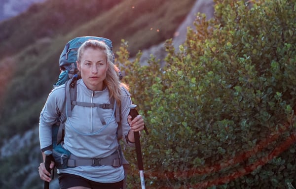 White woman walking with a backpack on a trail